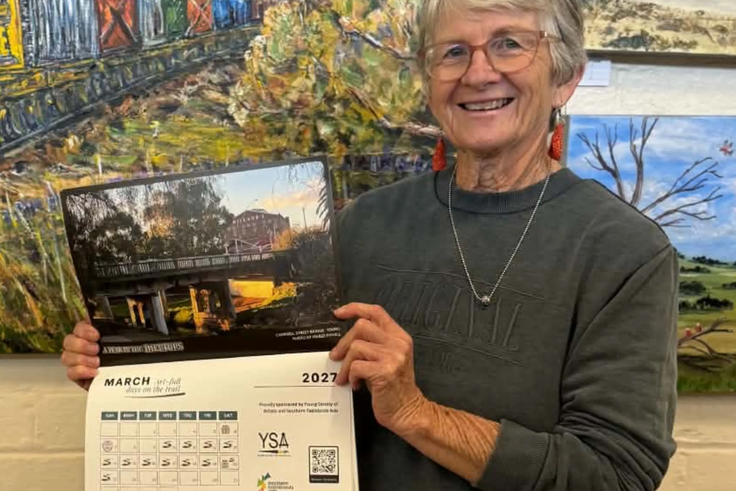 <p>Young Society of Artists member Heather Ruhl showcases the 2027 A Year in the Hilltops calendar at the Young Show. Proceeds from calendar sales will support the 2027 Hilltops Off The Beaten Track Arts & Cultural Trail.</p>\\n